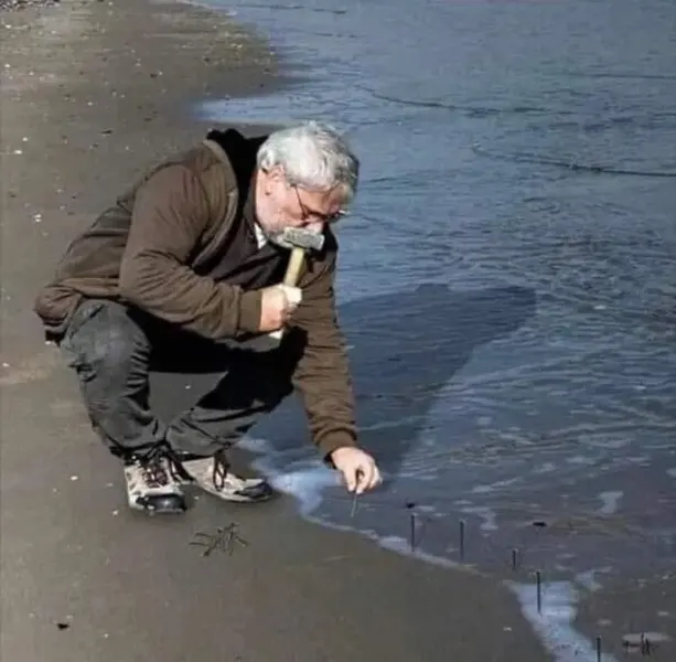 Guy Hammering Nails Into Sand blank meme template